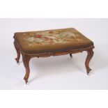 A Victorian walnut boudoir stool,  the floral needlepoint upholstery above a shaped frieze,