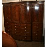 An early 19th Century mahogany bow fronted breakfront wardrobe, surmounted by a stepped cornice,