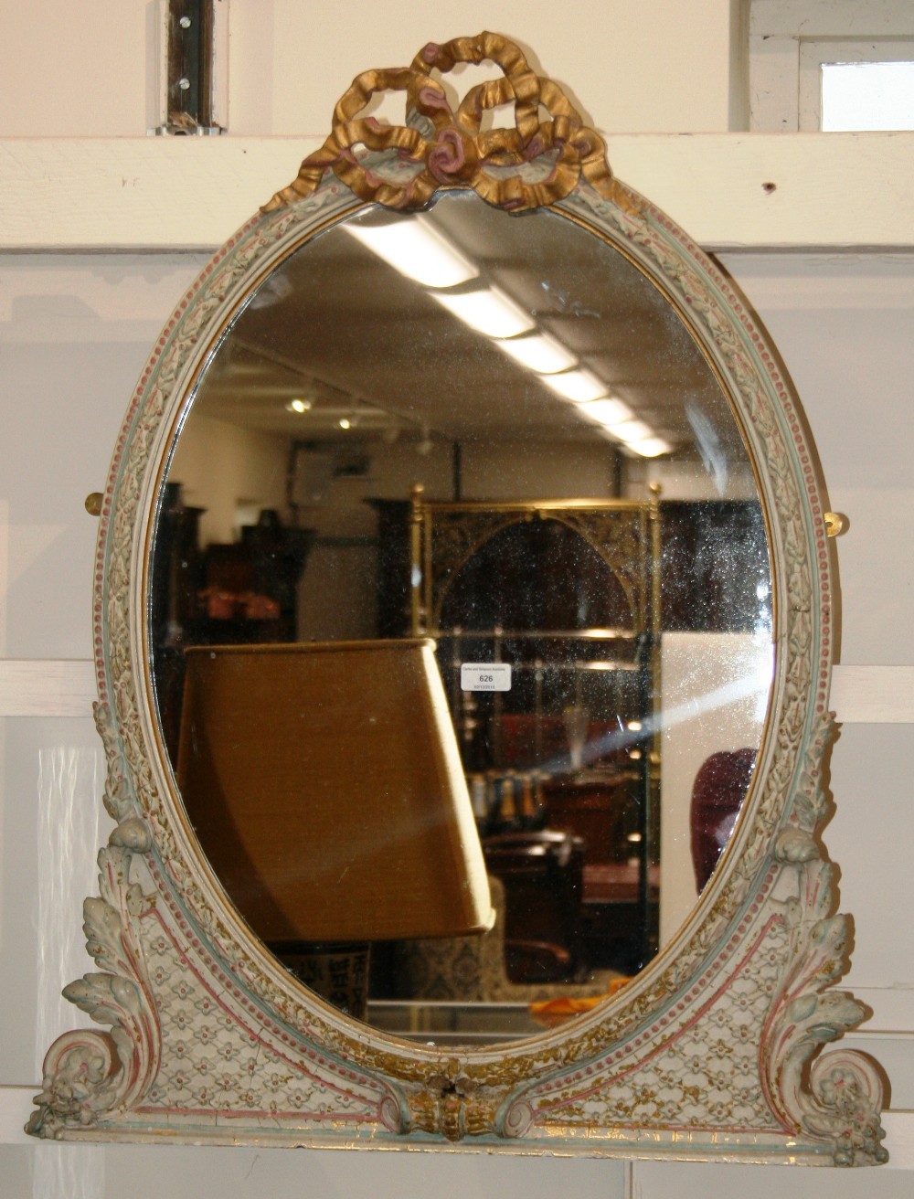 A 19th Century oval painted wall mirror, decorated foliate scrolls and a ribbon tied surmount,