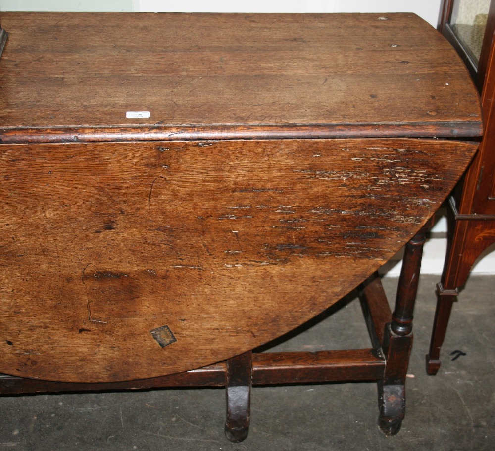 An Antique oak gate leg dining table, having rounded drop leaves,