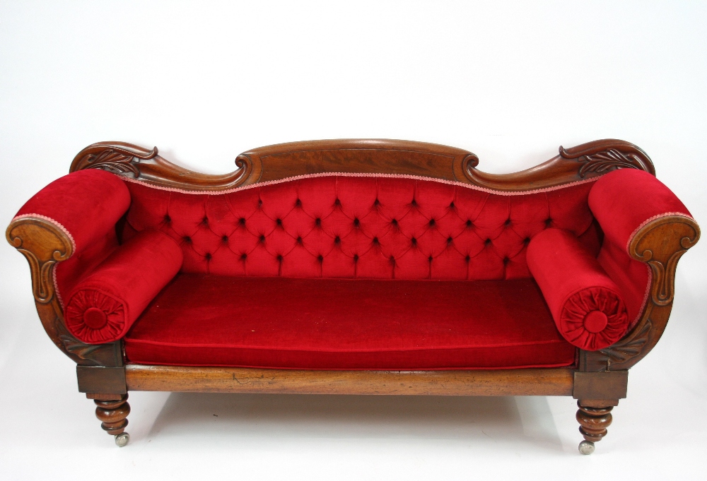 An early Victorian scroll end couch, with red velour upholstery, raised on turned supports,