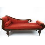 An early 19th Century mahogany chaise longue, with scrolled ends, upholstered in pink velour,