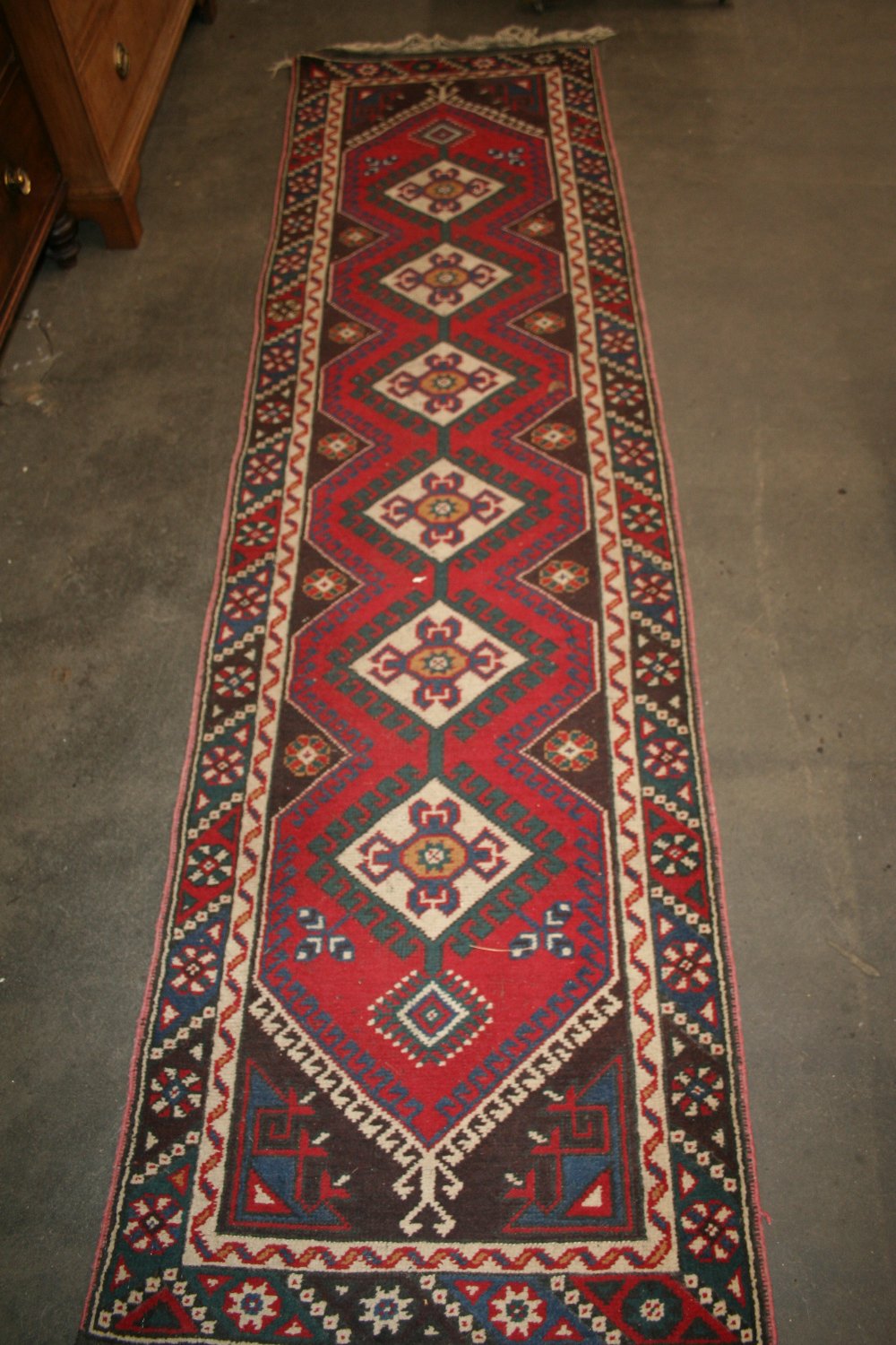 A Turkish runner, having central field of linked medallions on a red ground within stylised borders,