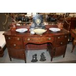 A 19th Century mahogany bow fronted sideboard, surmounted by a brass back rail with turned finials,
