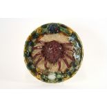 A Majolica style plate, with central encrusted decoration of a crab amongst shells and sea foliage,