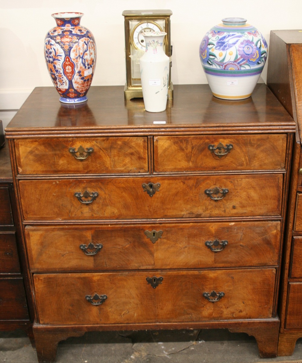 An 18th Century walnut chest, fitted two short and three long drawers, raised on bracket supports,