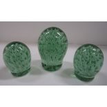 A tall waisted green glass dump with bubble burst decoration 14cm, and two similar smaller dumps [