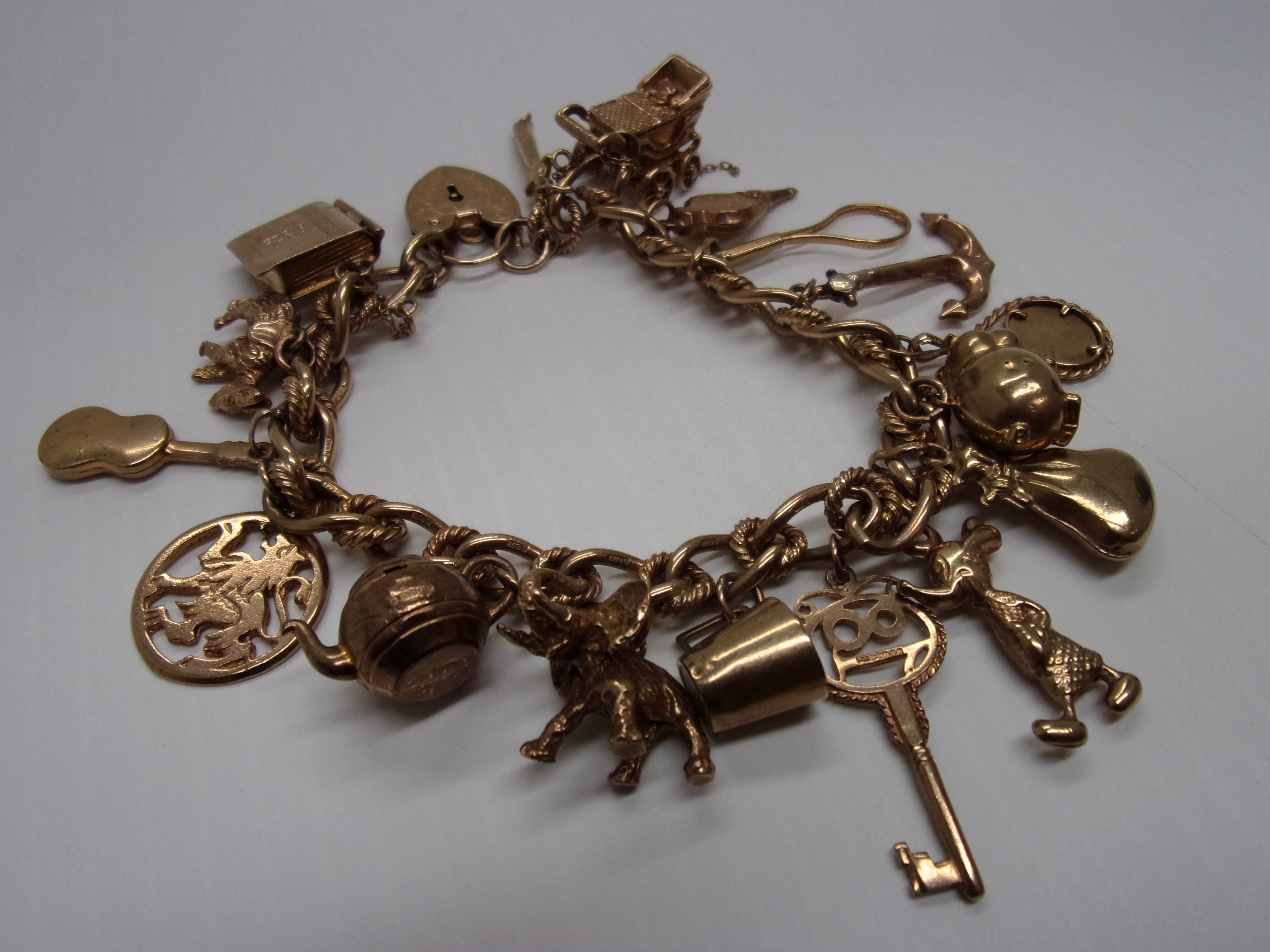 A 9ct gold fancy curb link bracelet hung with charms. Further Information Approx 50g/1.7oz