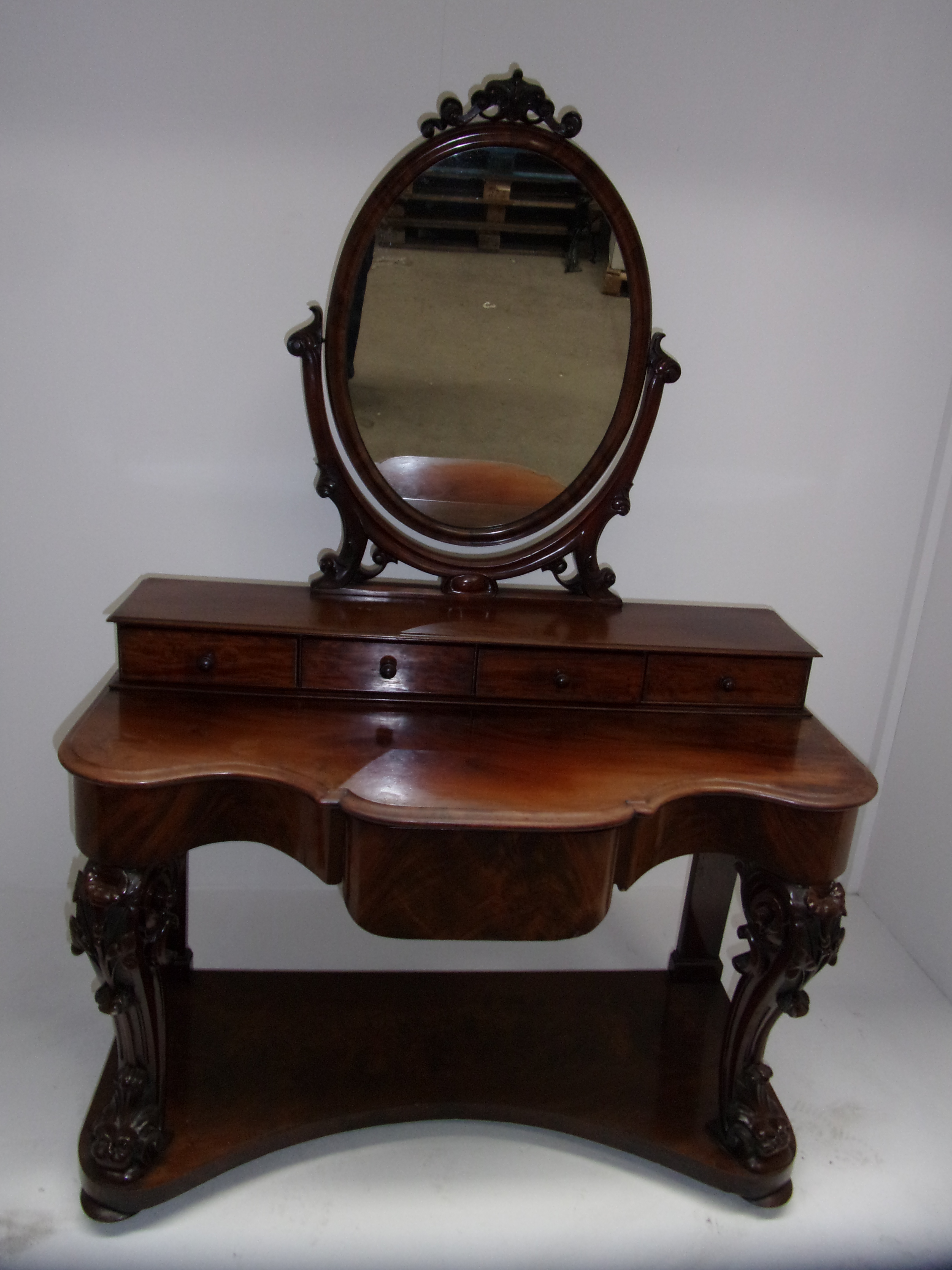 A Victorian mahogany Duchess dressing table with oval mirror over four drawers, shaped front and