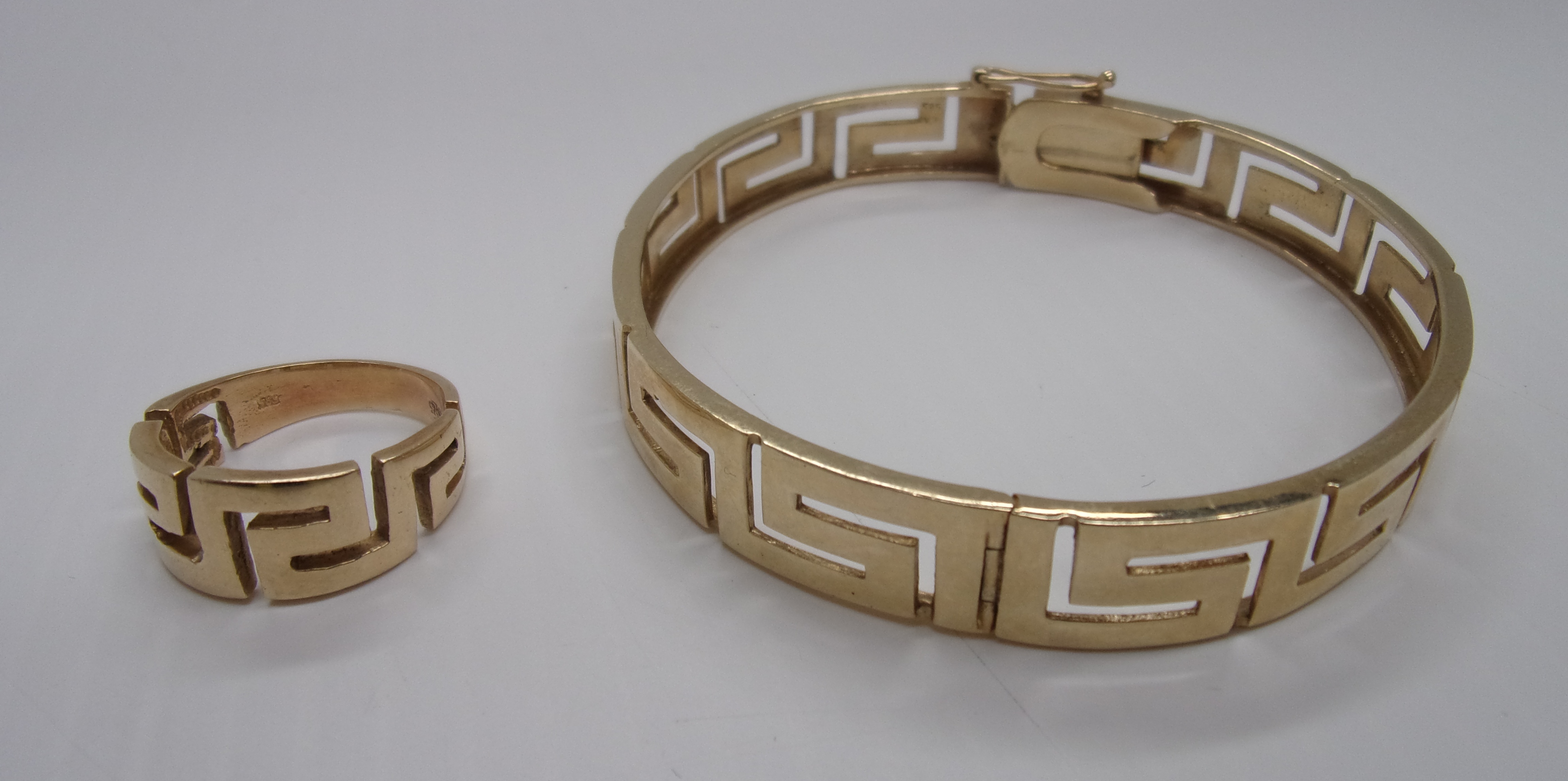 A gold bangle pierced in key pattern, st