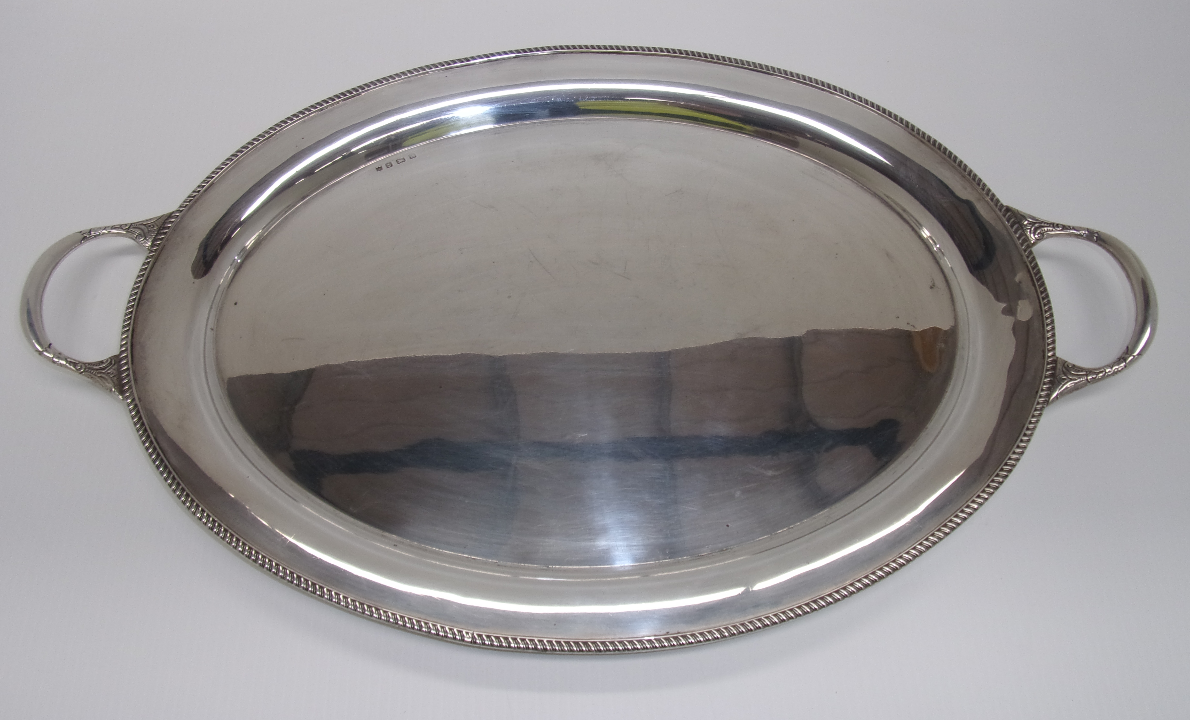 An oval silver tray with gadroon edge an