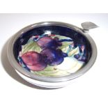 A Moorcroft circular ashtray in Wisteria design on a dark blue ground with applied plated rim -