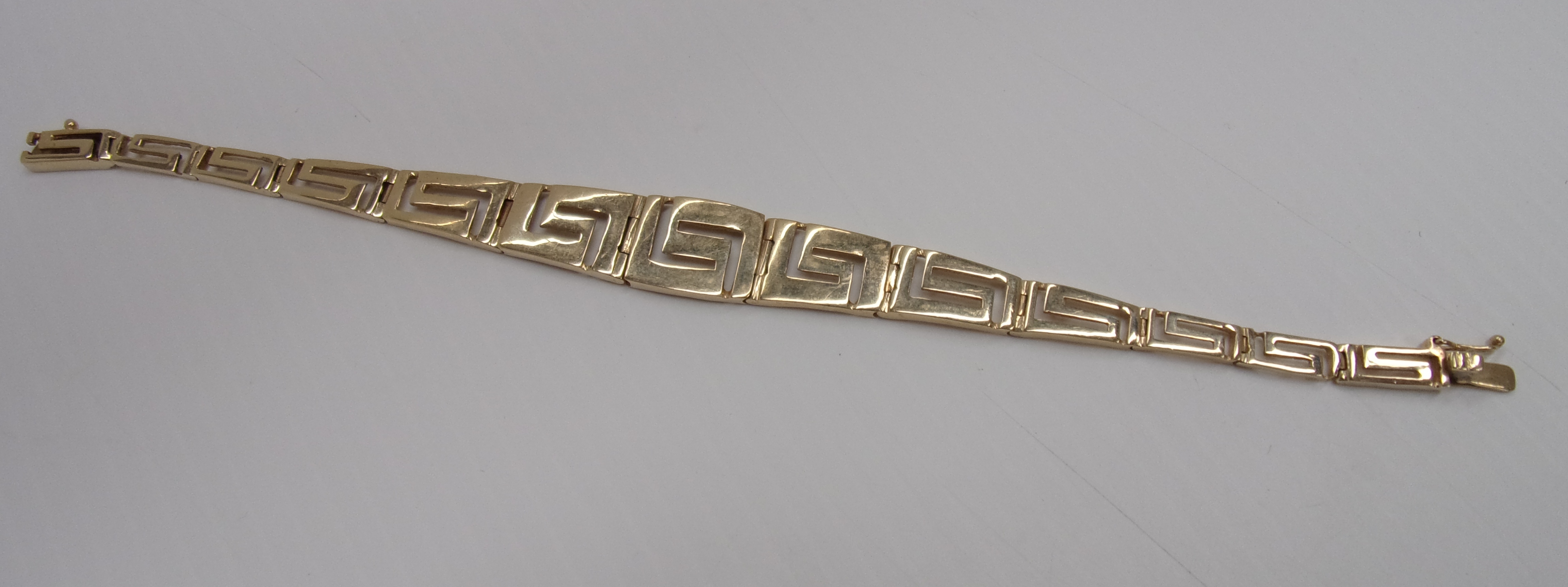 A gold bracelet of graduated key pattern