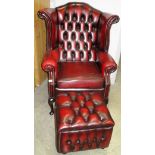 An Oxblood reproduction wing back armchair with deep buttoned back and a matching pouffe (2)