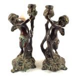 A pair of 19th Century decoratively cast Bronze cherub candlesticks,