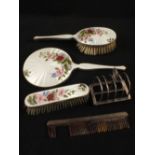 A small Silver toast rack and a Silver and floral enamel brush and mirror set