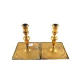 A pair of late 17th Century Spanish Brass candlesticks on wide square bases with ring turnings,