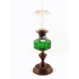 An embossed Brass oil lamp with green glass bowl and etched globe