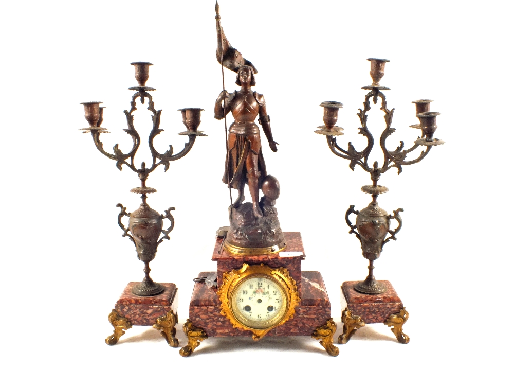 A striking clock garniture with spelter figure of Joan of Arc with floral painted porcelain dial on