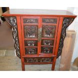 A lacquered Chinese two door cabinet with carved panelled decoration