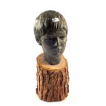 A pottery bust of a boy on a wooden base