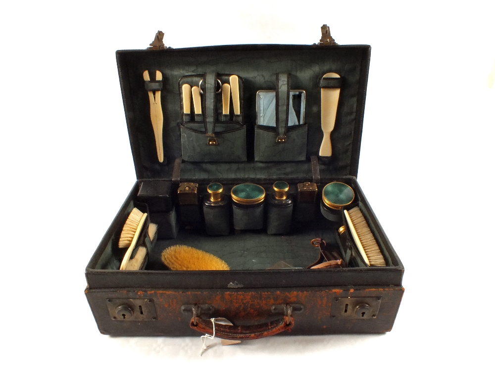 A leather travelling toilet case with green enamel top jars and Ivory and other fittings