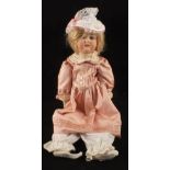 A German porcelain dressed doll marked CK 165/8 and a domed trunk containing a quantity of clothes