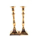 A pair of Georgian Brass or gun metal candlesticks with knopped stems and square bases,