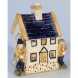 A Prattware cottage money box, of typical form centred by a moulded chimney with reverse coin