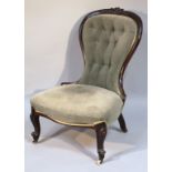 A Victorian mahogany nursing chair, the moulded ebonised back carved with stylized scrolls above