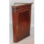 An 18thC oak hanging corner cupboard, the moulded door revealing a fitted interior with three