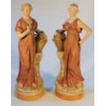 A pair of late 19thC Royal Dux figures, each formed as female water carriers beside urns on