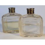 A pair of George V silver and cut glass perfume bottles, each with circular part engraved lids,