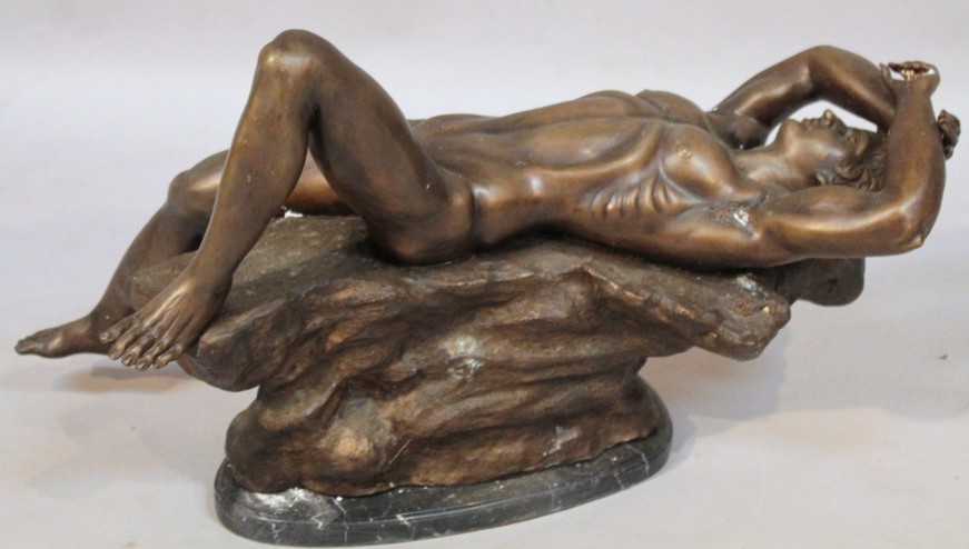 A bronzed figure, of a reclining nude male on a naturalistic rock work base and a textured marbled - Image 2 of 2
