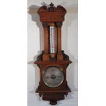 An Edwardian oak barometer and thermometer, the wide architectural case carved with scrolls and