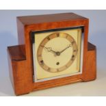 An Art Deco walnut cased mantel clock, the 13cm dia. circular dial, with Roman numerals, revealing a