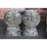 A pair of stone gate finials, each of orb form raised on circular squat stems terminating in