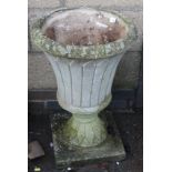 A stone planter, of Grecian urn form, on a square base with textured body, of 20thC construction,