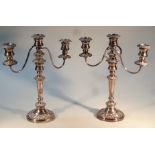 A pair of silver plated three branch candelabra, each of circular form, with floral outlines on