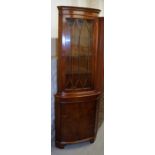 A yew wood finish corner cabinet, of freestanding form, with a fixed dentil cornice raised above