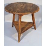 A George III style stained elm cricket table, the circular topped raised on tapering supports joined