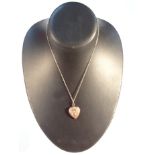 A heart shaped pendant, with blood stone back raised with flowers, attached to a slender link chain,
