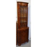 A yew wood finish corner cabinet, of freestanding form, with a fixed dentil cornice raised above a