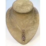 A late Victorian diamond drop pendant, surmounted by a cloverleaf, above pierced floral mounts, set