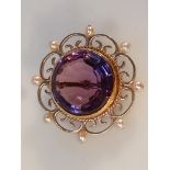An amethyst and seed pearl brooch, of shaped circular form, the floral outline broken by small