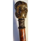 A polished wooden walking cane, with a spelter knop, set with a four sided head, 20thC, 93cm high.