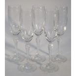 A set of five champagne flutes, each bowl part engraved with garlands and urns, on shaped stems