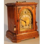 An Edwardian oak cased table clock, the 14.5cm back plate with a silvered circular dial set with