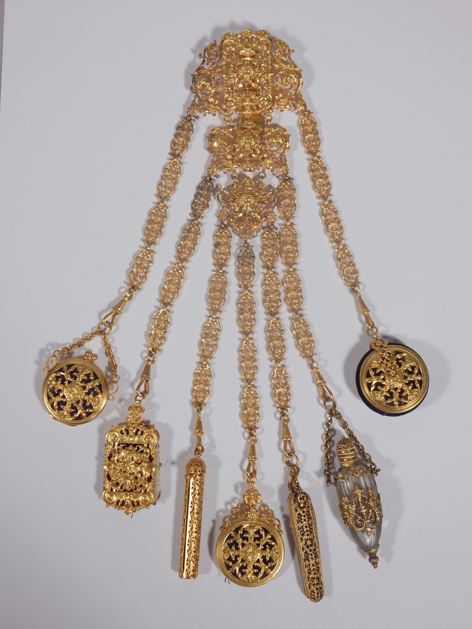 A late 19thC gilt metal chatelaine, elaborately cast in rococo style, the seven chains attached with