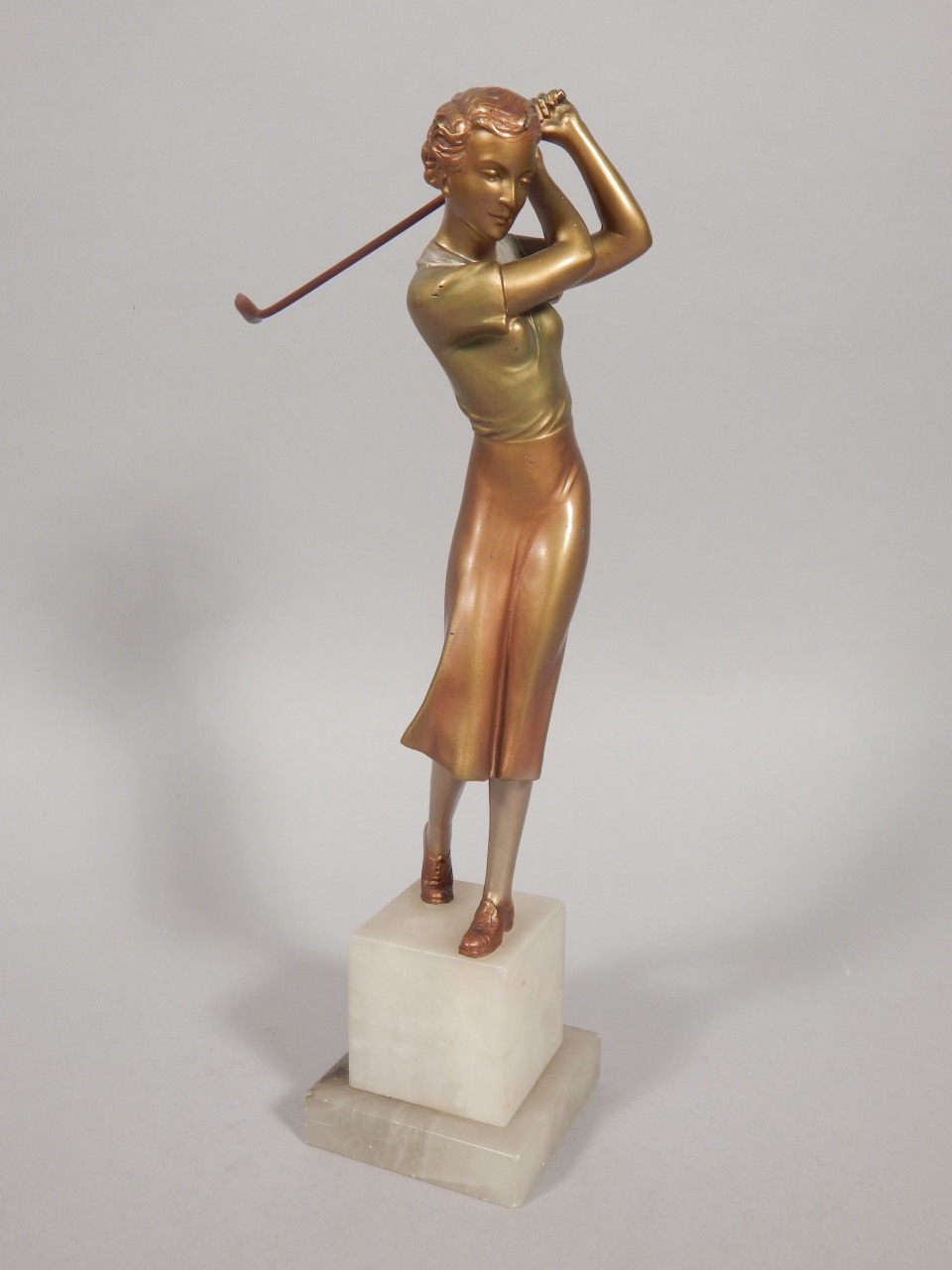 An Art Deco cold painted bronze figure of a female golfer, on a stepped onyx base, unmarked, 26cm